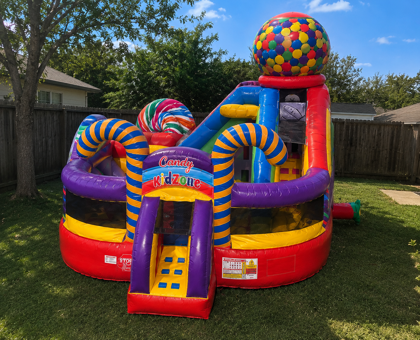Colorful inflatable playground structure with candy-themed design in a backyard.