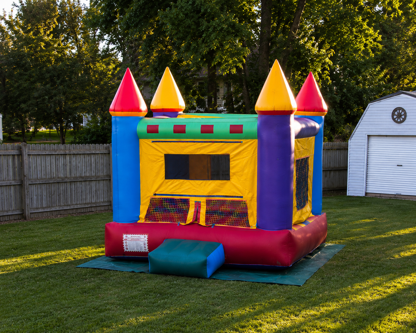Colorful inflatable bounce house with castle design on a grassy area.