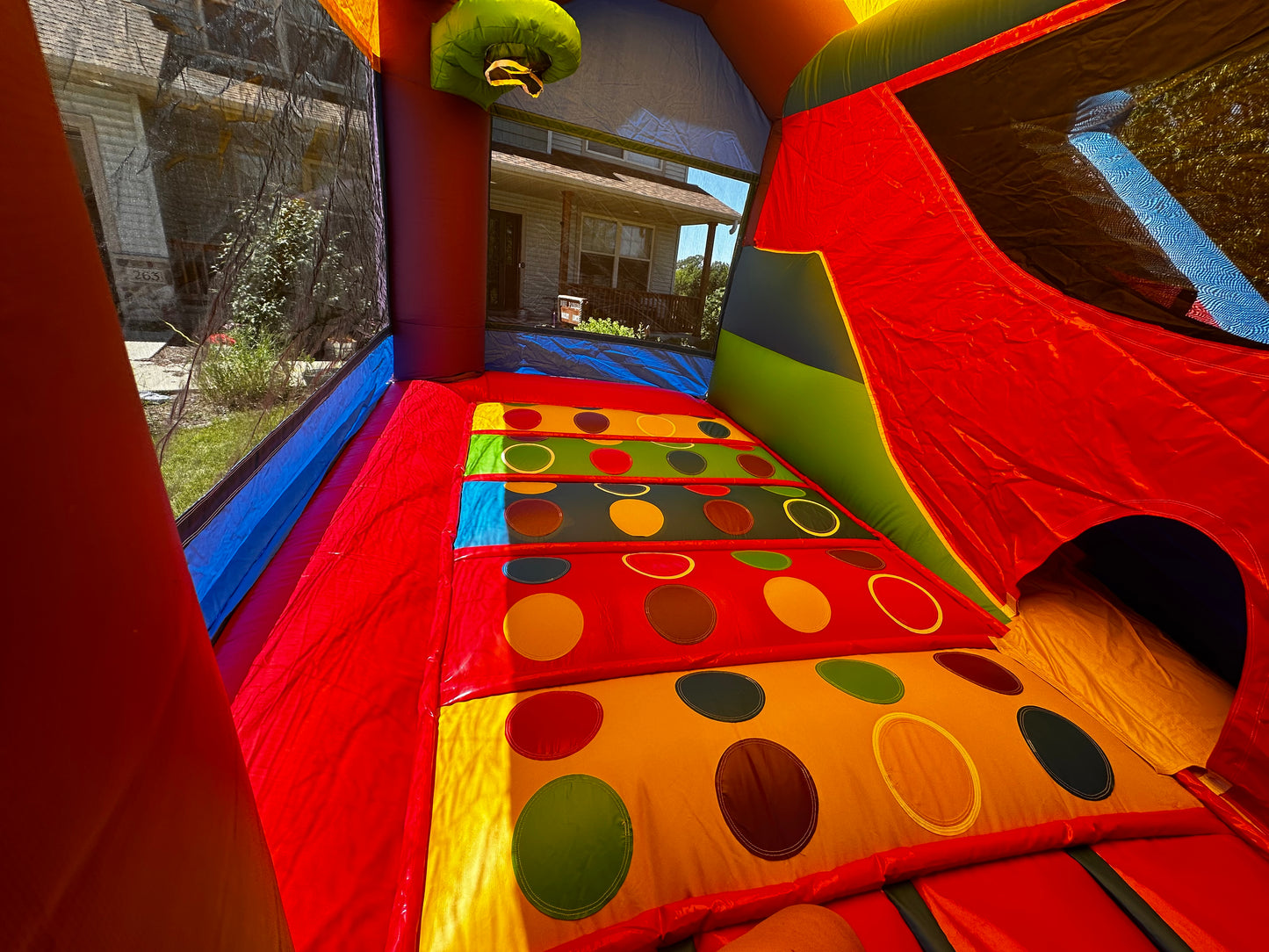 Interior of a bounce house with colorful circular patterns, bright red, yellow, and blue walls, and ample space for kids to jump and play.