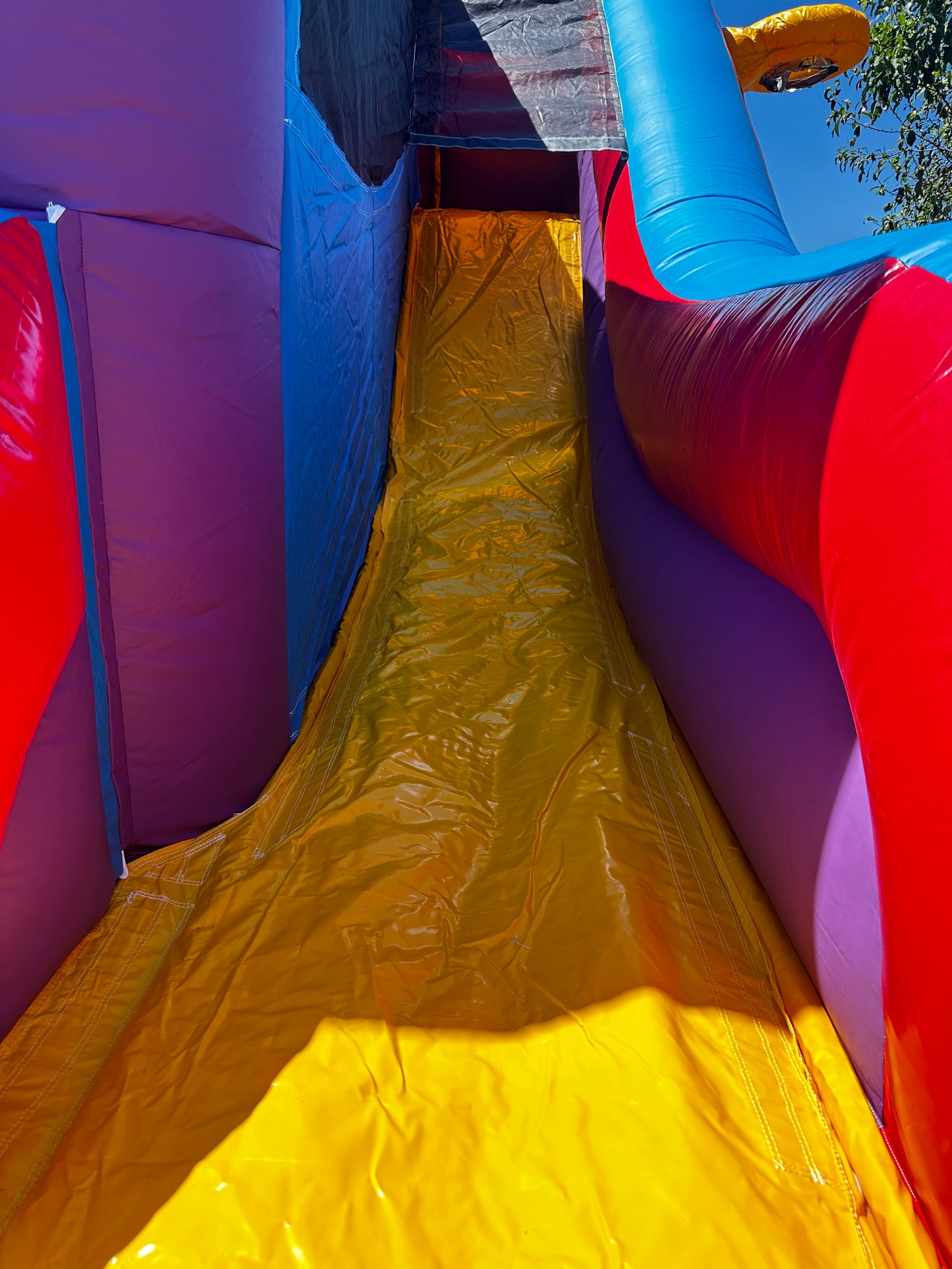 Bright yellow slide inside a colorful bounce house with red, blue, and purple walls, offering a fun and safe activity for kids at parties.