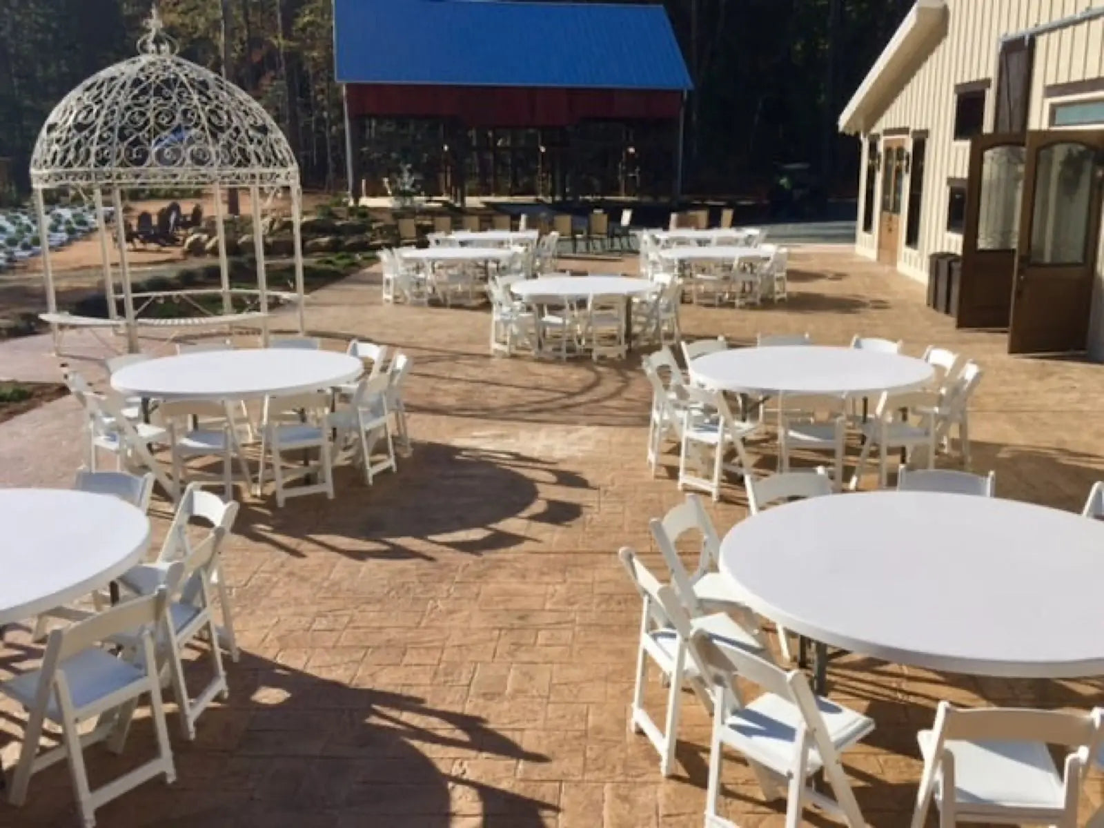 White folding chairs and round tables set up on a patio, perfect for outdoor weddings and events, creating a picturesque setting.