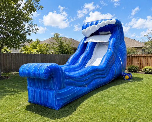 Blue inflatable water slide with a shark mouth design on a grassy lawn.